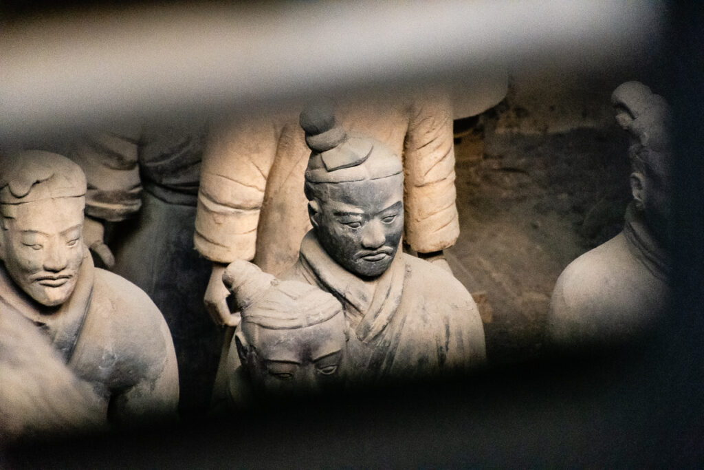 Close-up ravvicinato su un piccolo gruppo di statue in terracotta dell’esercito di Qin Shi Huang, con volti scolpiti in modo unico.