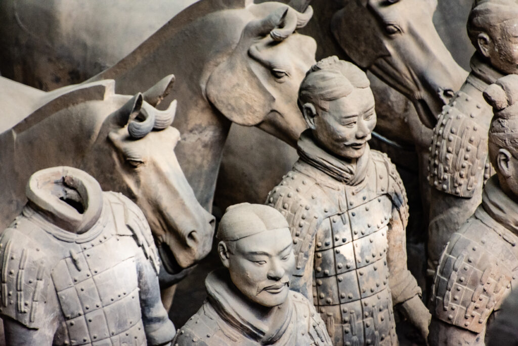 Dettaglio ravvicinato su un gruppo di statue in terracotta dell’esercito di Qin Shi Huang, con guerrieri affiancati da cavalli scolpiti a grandezza naturale.