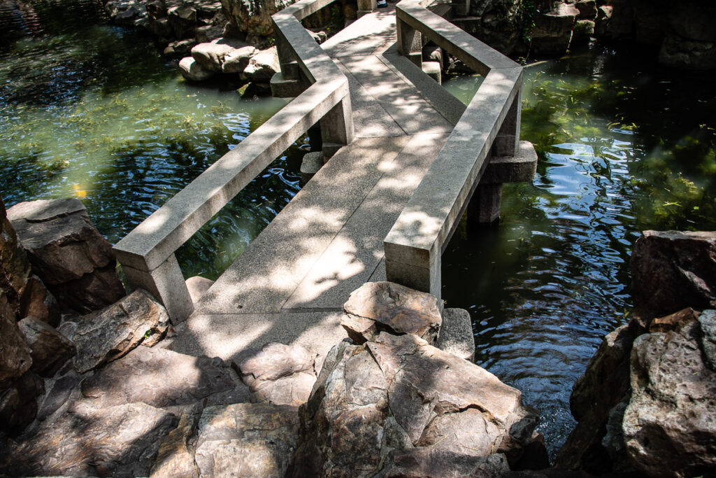 Ponte a zig-zag nel Giardino del Mandarino Yu a Shanghai, circondato da laghetti, salici e padiglioni tradizionali.