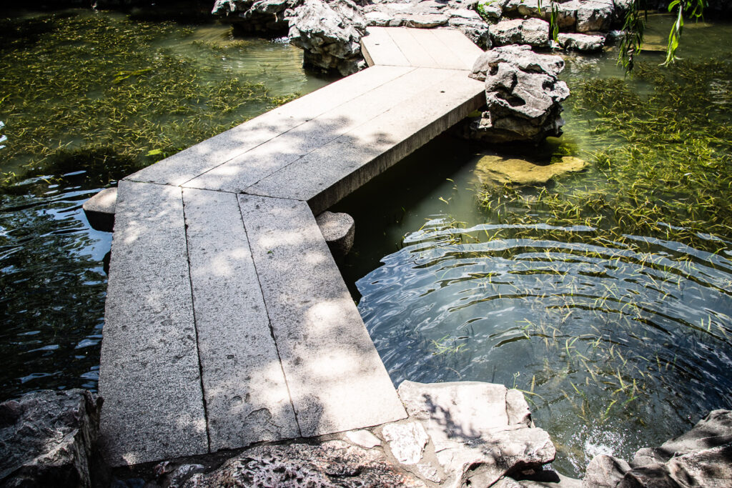 Ponte a zig-zag nel Giardino del Mandarino Yu a Shanghai, circondato da laghetti, salici e padiglioni tradizionali.