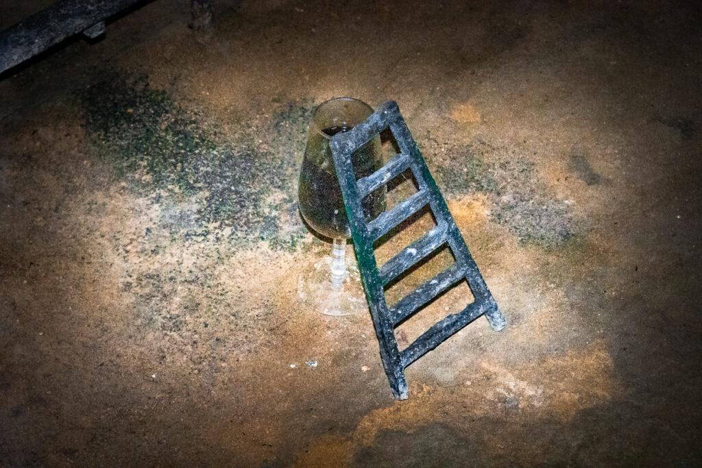 Piccola scaletta appoggiata a un bicchiere di sherry sul pavimento delle Bodegas González Byass a Jerez.