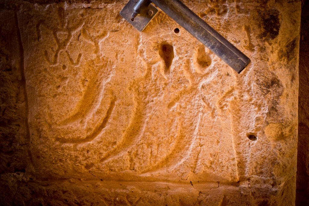 Primo piano di tre pugnali a lama ricurva scolpiti su un blocco di pietra dell’anfiteatro di El Jem.