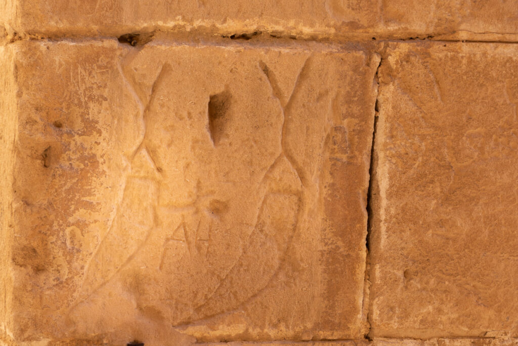 Grande incisione consumata a forma di pugnale curvo su una pietra dell’anfiteatro di El Jem.